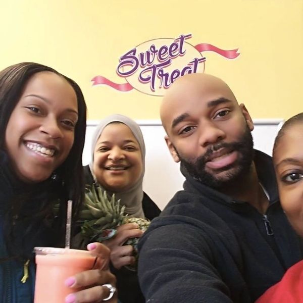 A group of people posing for a picture in front of a sign that says sweet treat