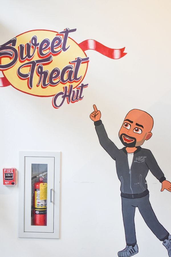 A cartoon of a man standing in front of a sign that says sweet treat hut