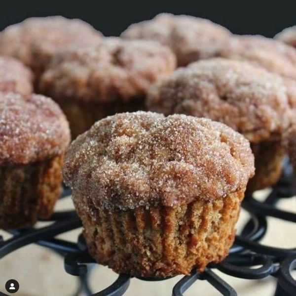 A bunch of cinnamon muffins are sitting on a wire rack