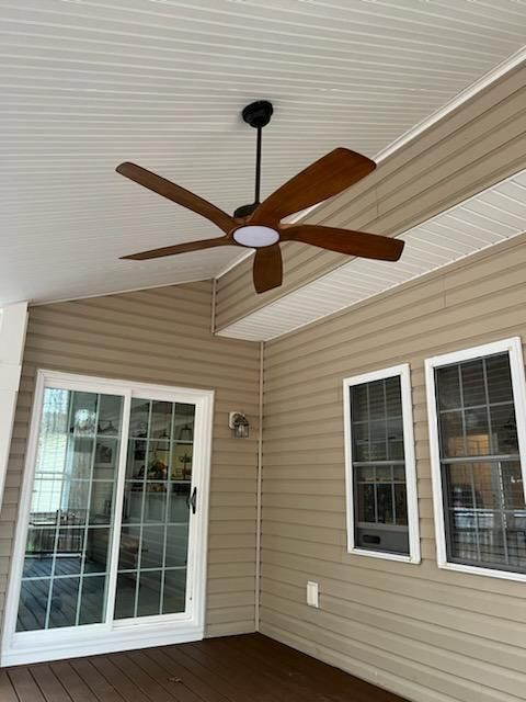 Covered porch with ceiling fan. Brown fan blades, tan siding, white sliding door and windows.