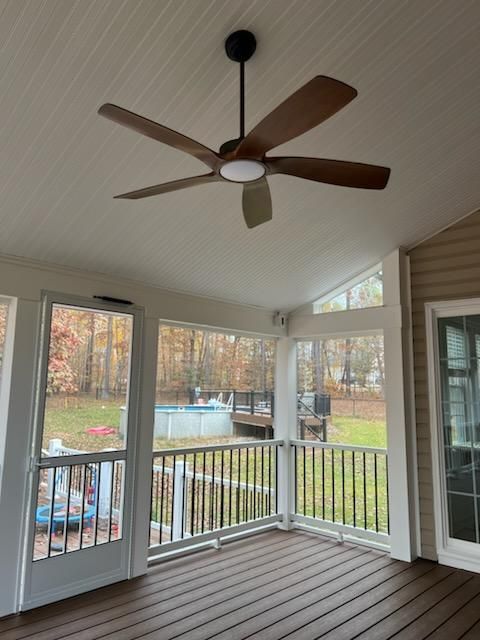 A screened-in porch with a ceiling fan. Outside is a yard and a swimming pool.