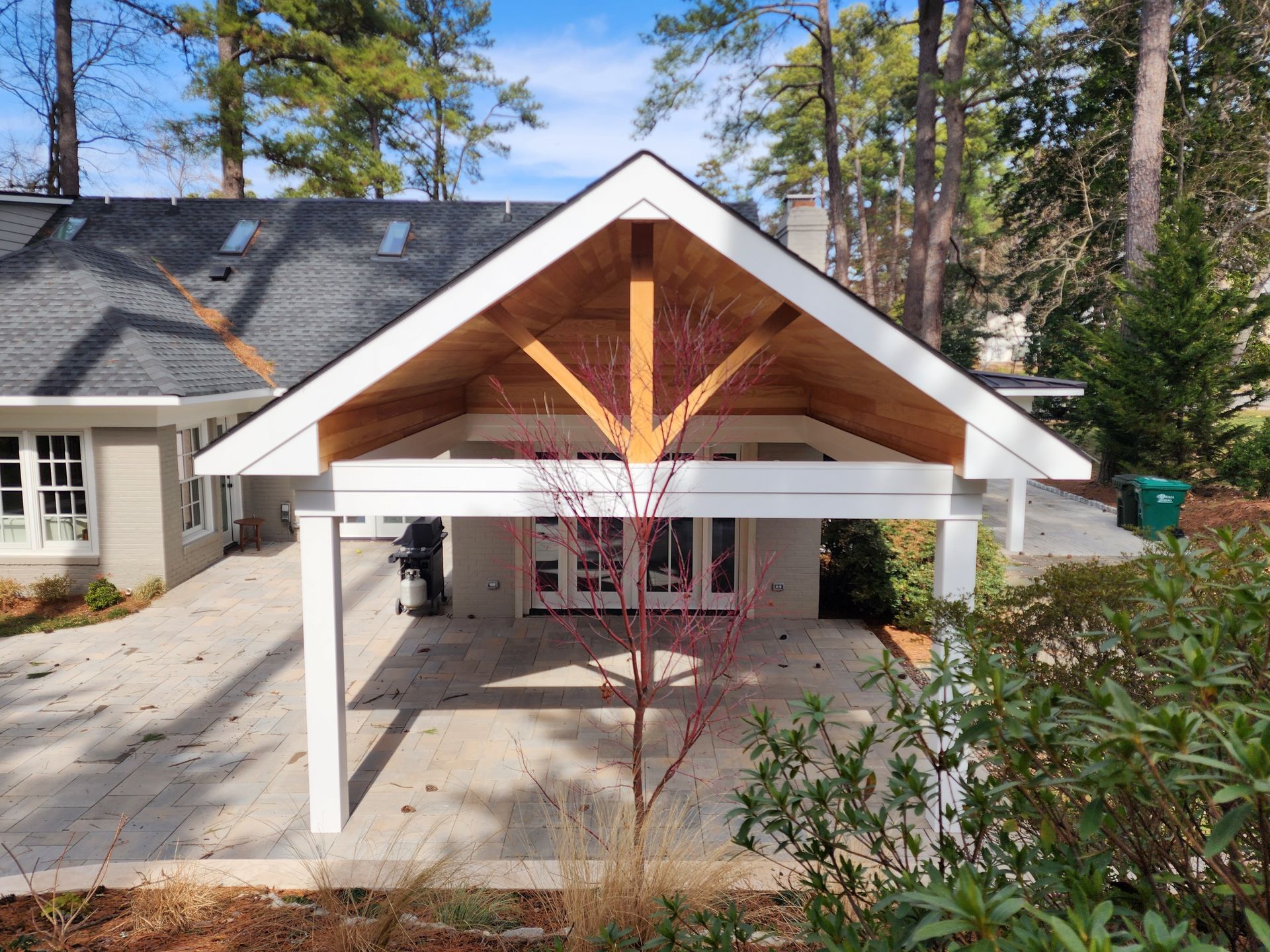 Patio cover attached to a house with white trim and a wooden truss.