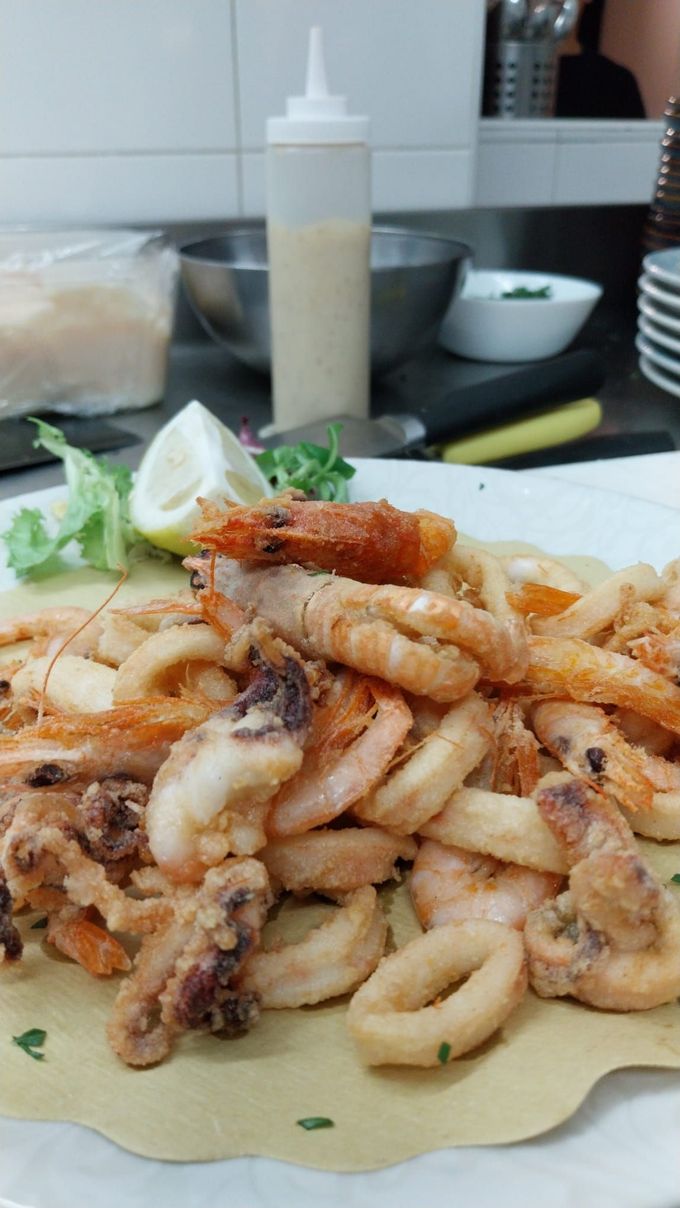 Piatto di calamari fritti con spicchio di limone e salsa d'accompagnamento su un tavolo di ristorante.