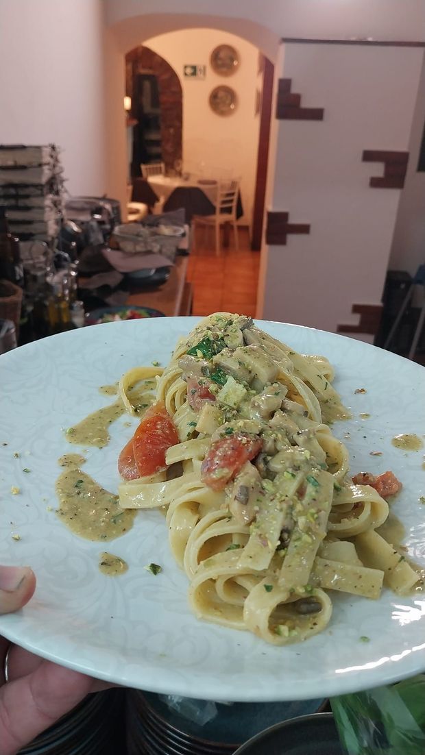 Un piatto di pasta con salsa cremosa e pomodori, in primo piano nell'accogliente interno di un ristorante.