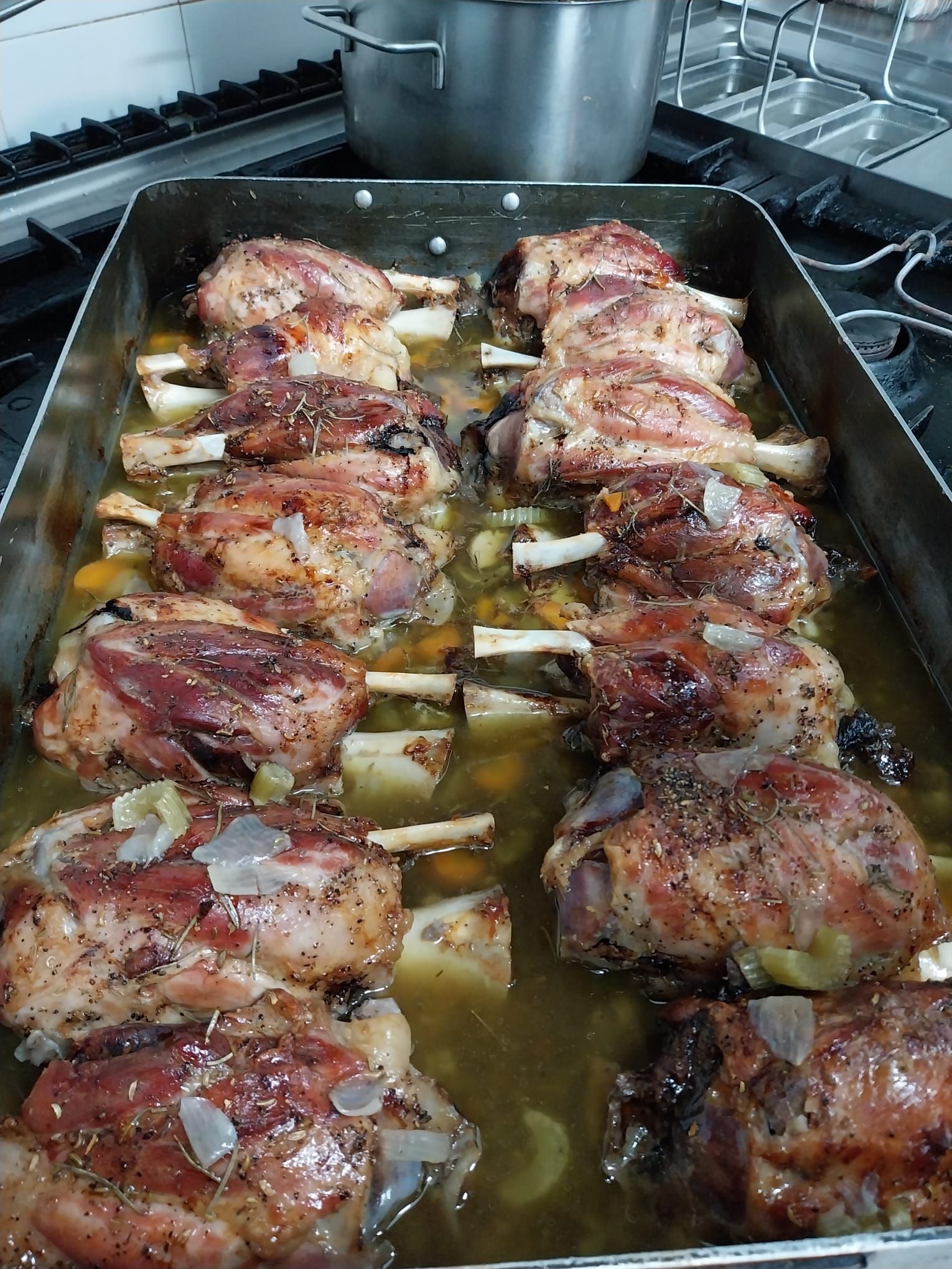 Pezzi di pollo cotti al forno su una teglia con erbe aromatiche e pelle dorata.