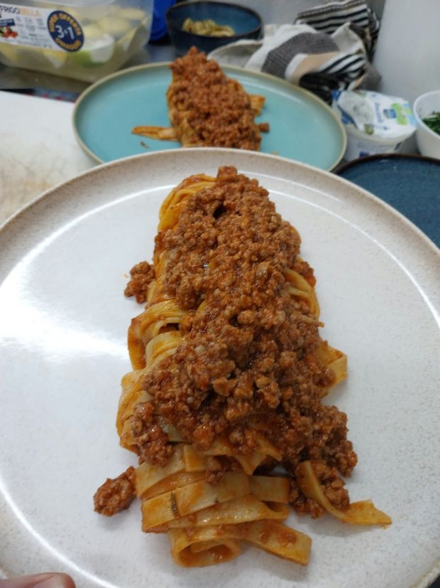 Pasta a conchiglia cremosa servita in una ciotola beige, guarnita con erbe aromatiche, formaggio e pangrattato.