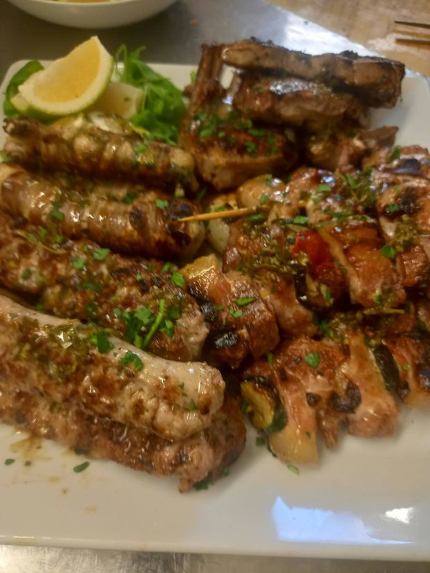 Antipasti assortiti su un piatto bianco, tra cui salse, insalata, fette di pane e una crocchetta.