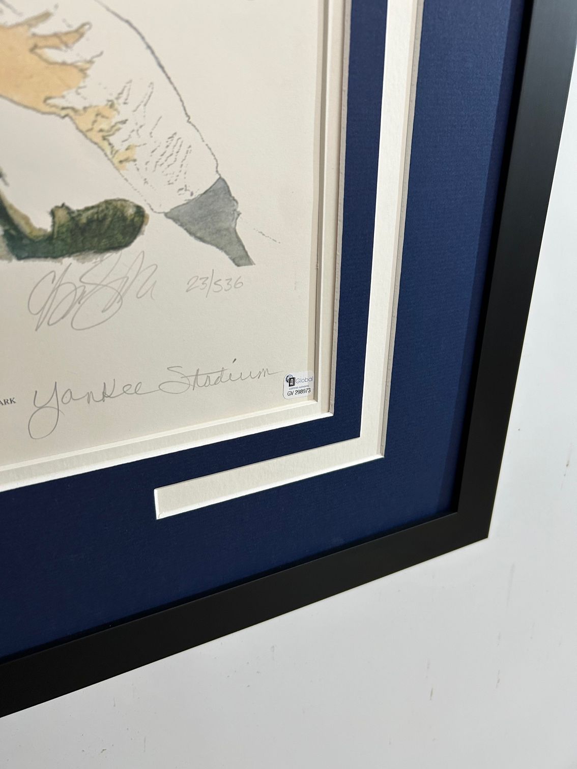 Framed baseball print with New York Yankees imagery and a batter in action on a dark blue mat.
