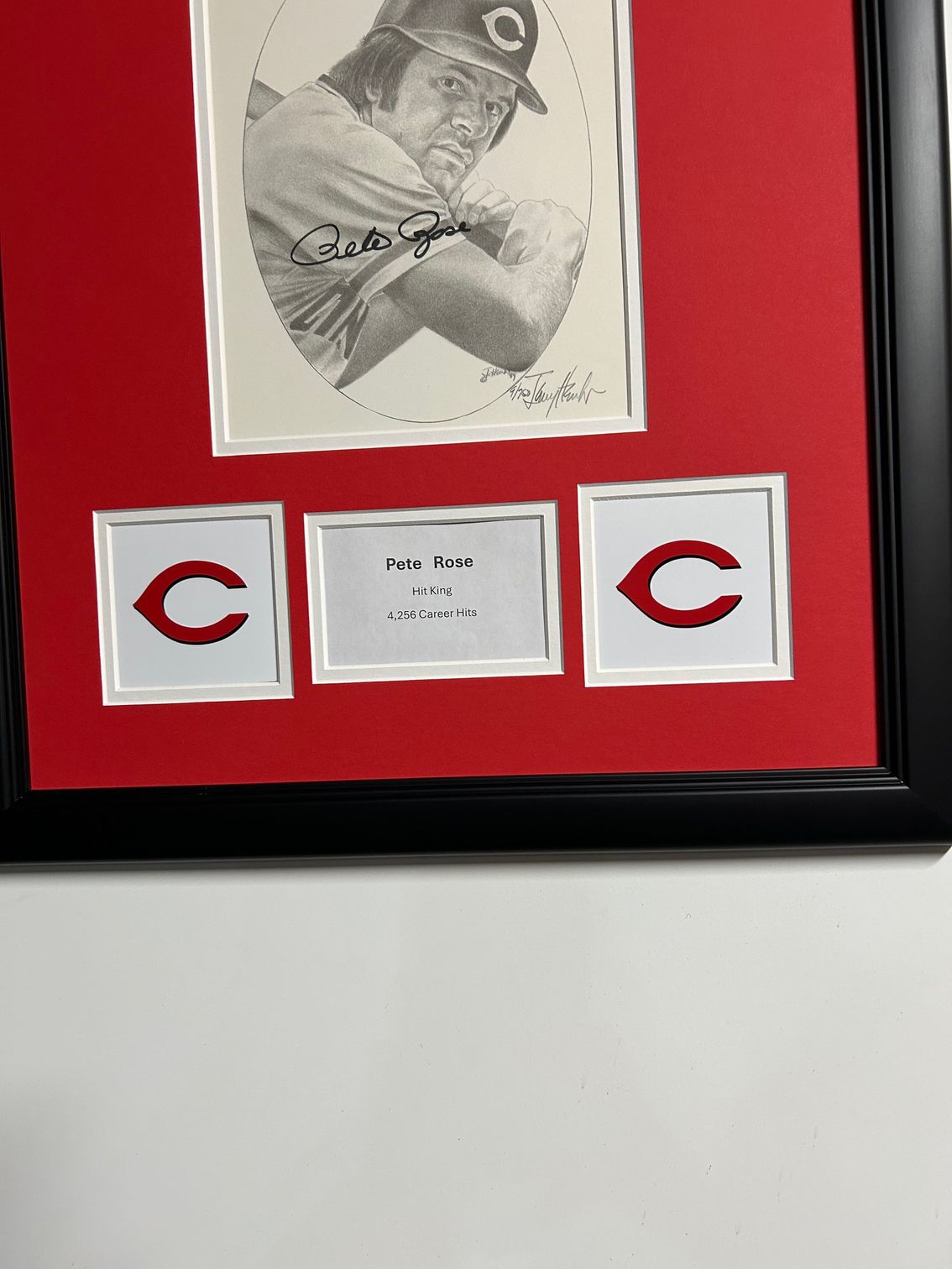 Framed black-and-red display with a sketch and two Cincinnati Reds logos around a center label