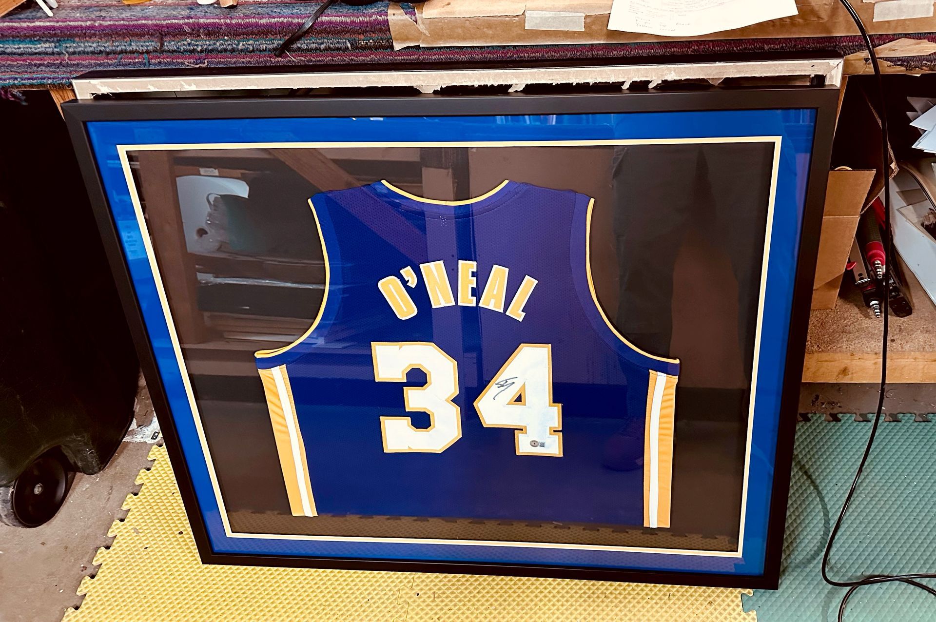 Framed blue basketball jersey with number 34 on display in a black frame
