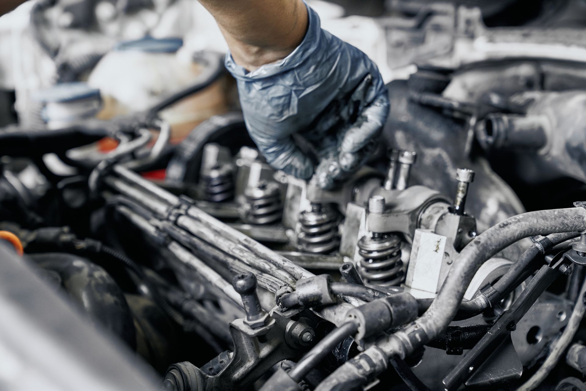 Close up of nozzles in car diesel engine with mechanic's hand in blue dirty rubber gloves doing professional auto repairing.