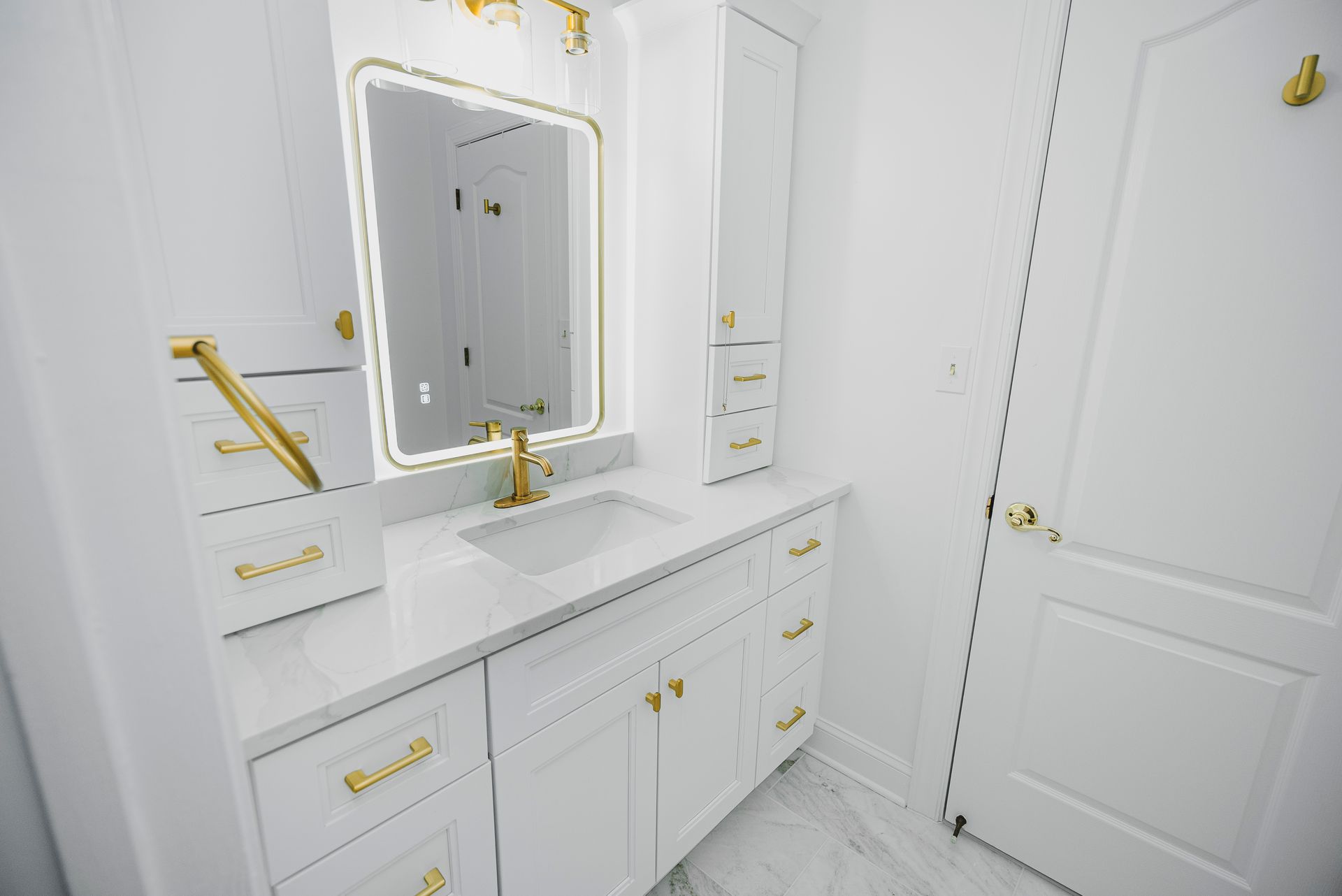Professional bathroom renovation showcasing custom storage towers and a backlit LED vanity mirror.