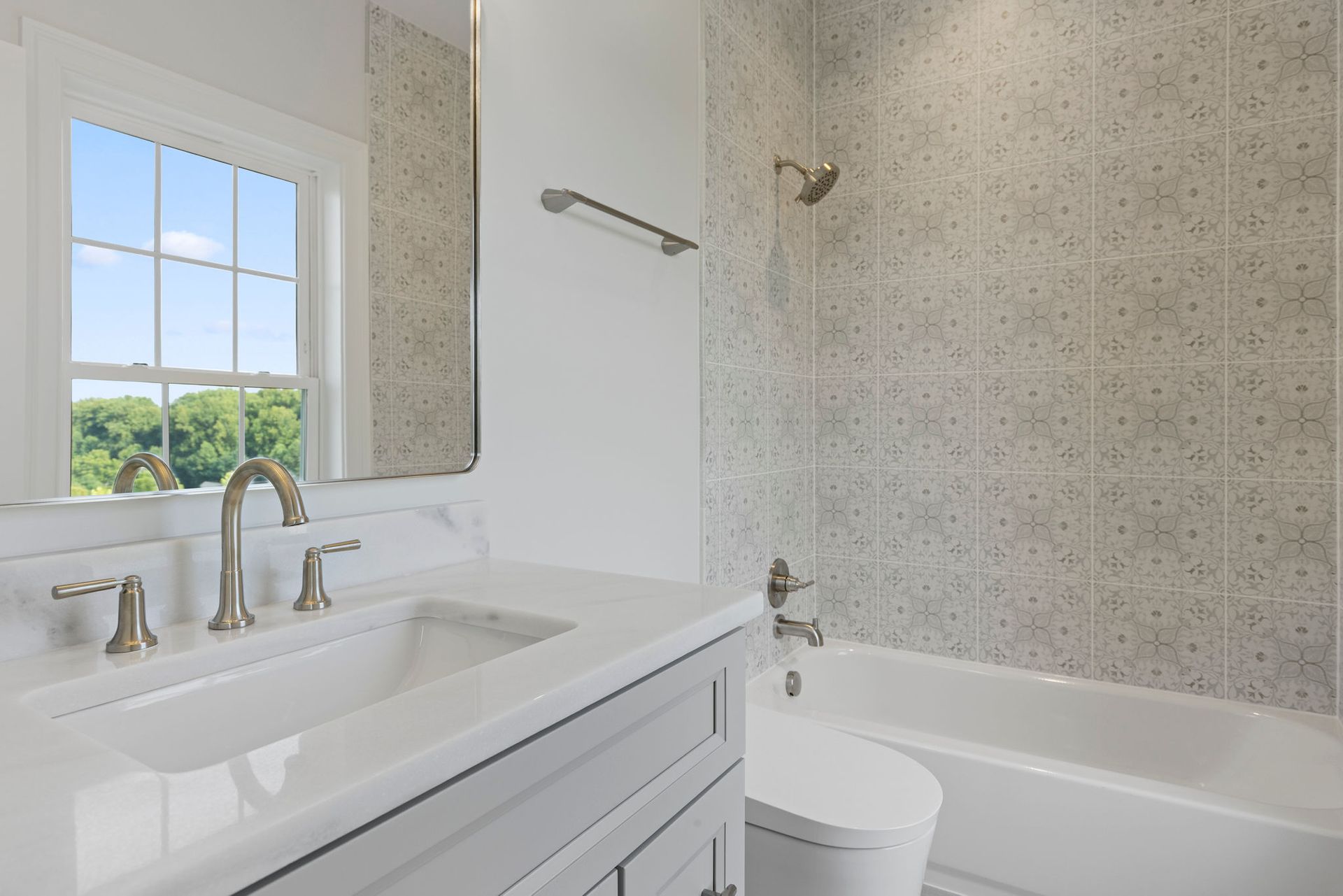 Bathroom remodeling: installing a new bathtub and shower combo with patterned wall tile and marble vanity.