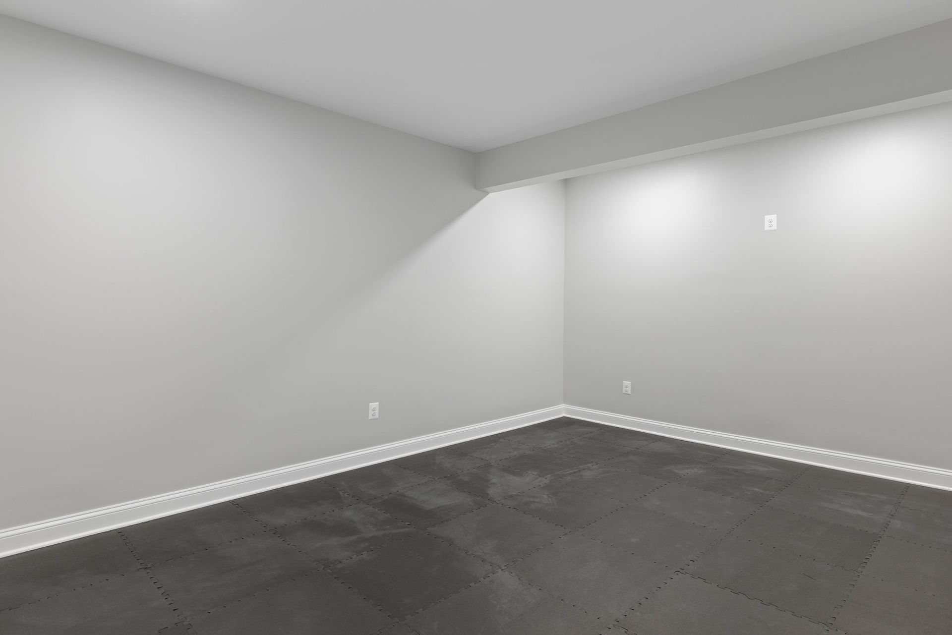 Finished basement space: home gym renovation with durable rubber flooring and custom overhead lighting.