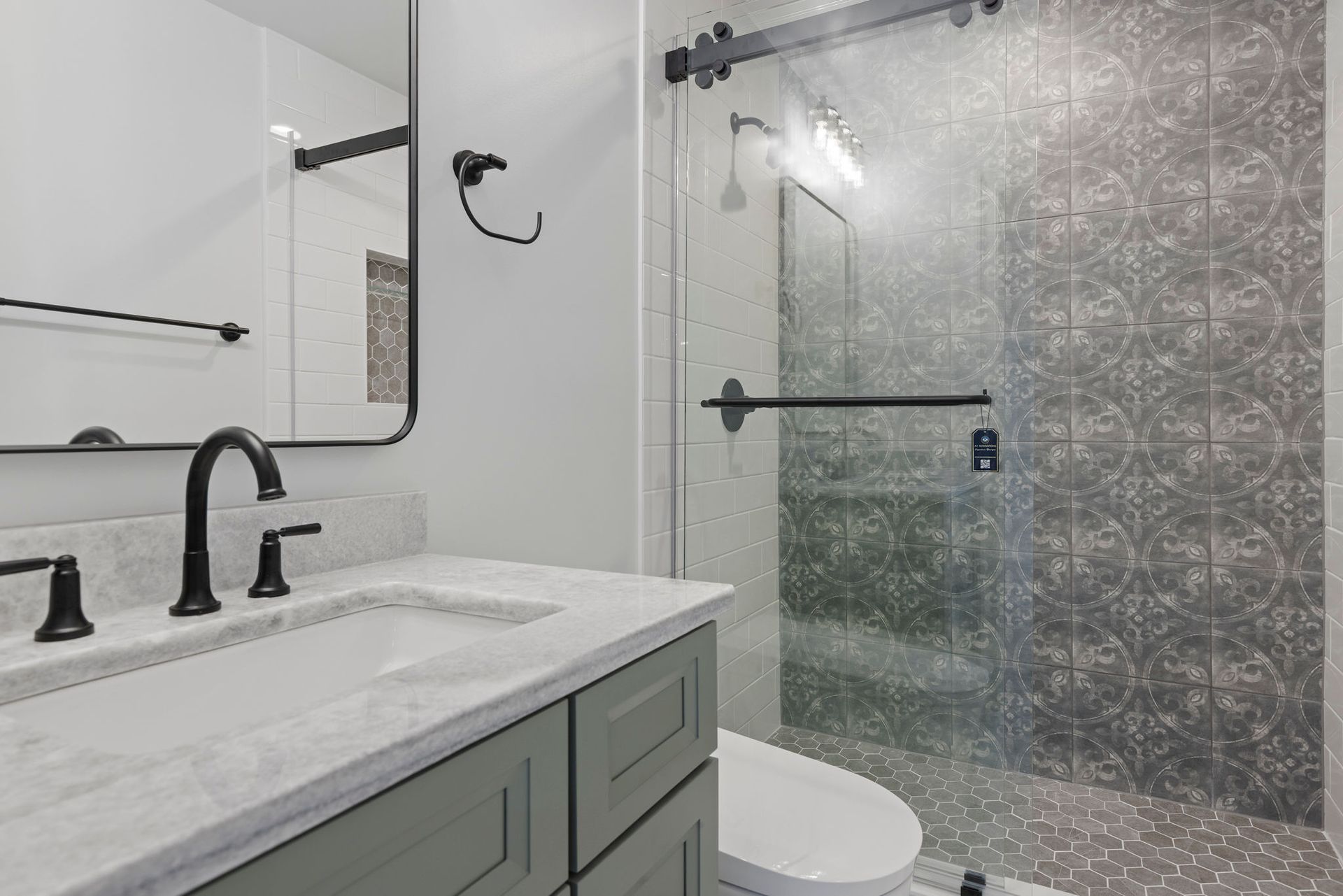 Modern shower remodeling: patterned wall tile, sliding glass door, and matte black fixtures for a striking bathroom upgrade.