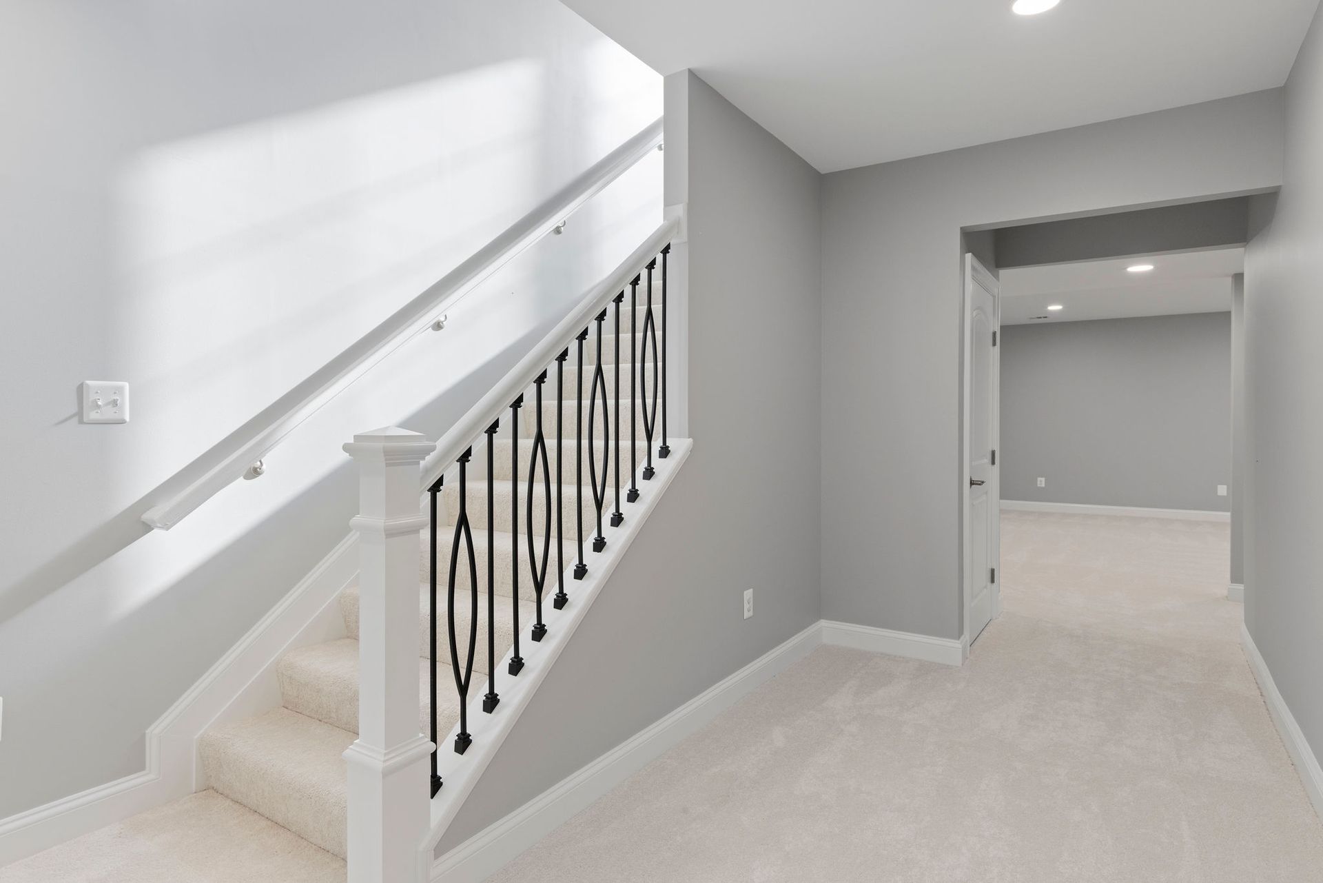 Basement stairwell finishing: installing carpeted stairs, modern iron baluster railing, and newel posts.