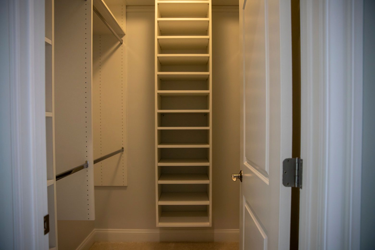 Custom closet organization system: built-in shelving and hanging rods for a primary bedroom closet.