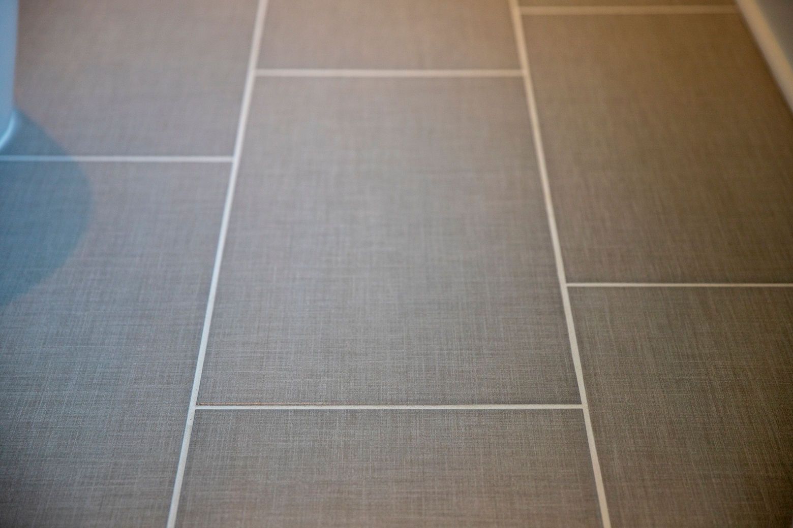  A close-up of the new nickel gold tub faucet and handheld shower on a patterned tile background.