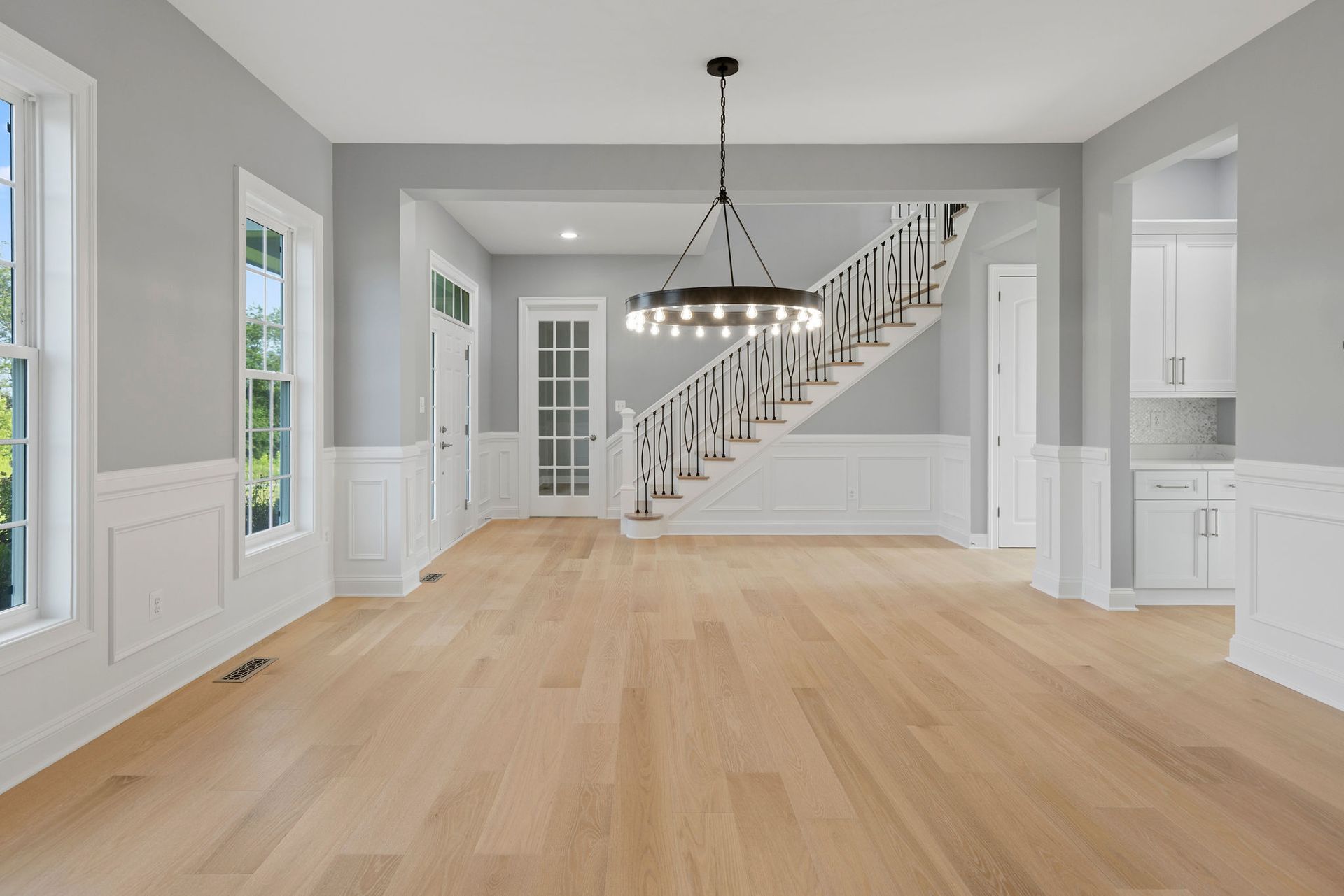 Entryway and staircase renovation ideas: modern iron railing installation and custom trim accent wall.