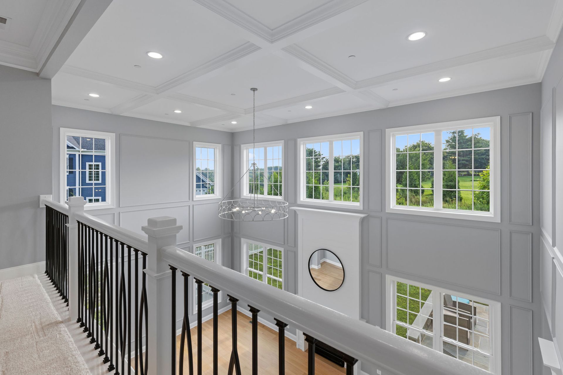 Custom upstairs hallway renovation: coffered ceiling remodel, iron railing, and decorative wall paneling.
