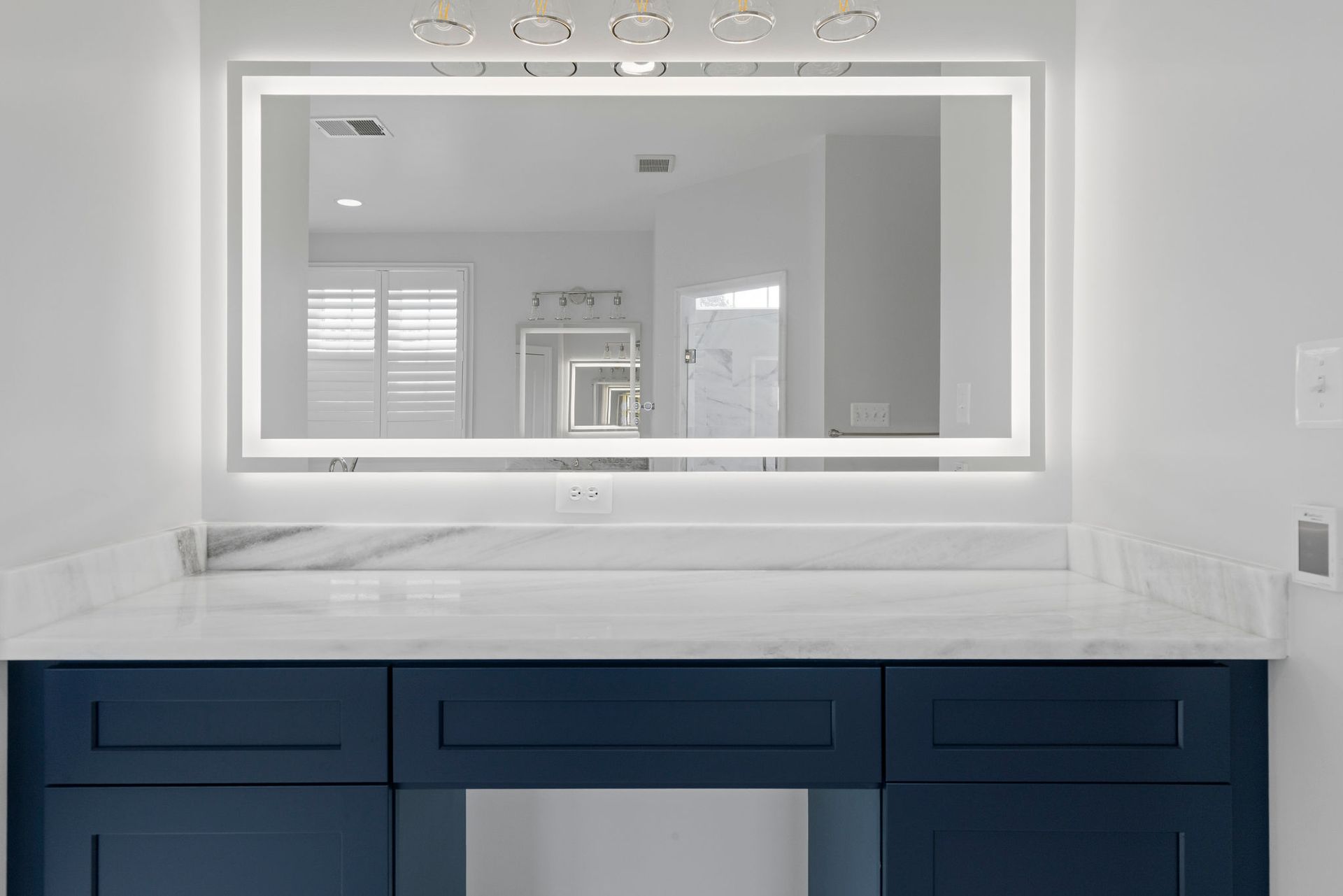 Bathroom lighting and mirrors: installing modern backlit mirror and marble vanity counter for a luxury bathroom.