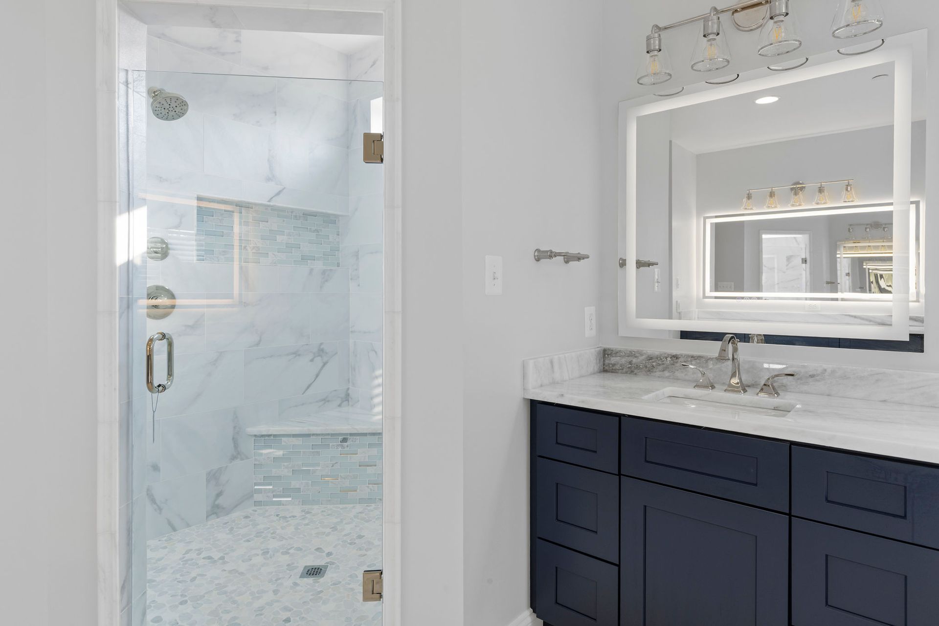 Walk-in shower renovation: custom glass door, marble tile, and mosaic shower pan installation.