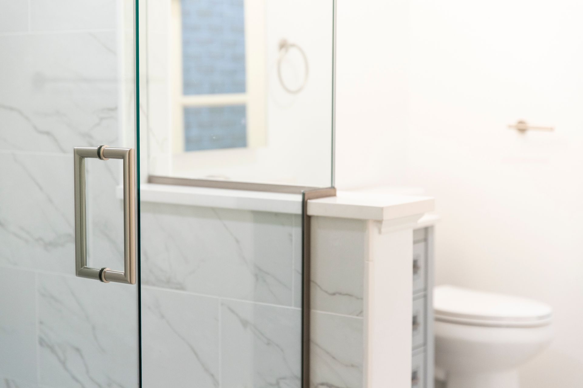 A close-up of a brushed metal faucet on a white marble-style countertop.