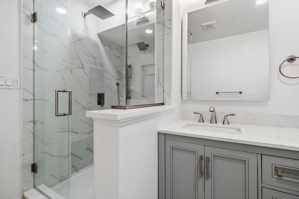 A gray bathroom vanity with a white marble-style countertop and a brushed metal faucet.