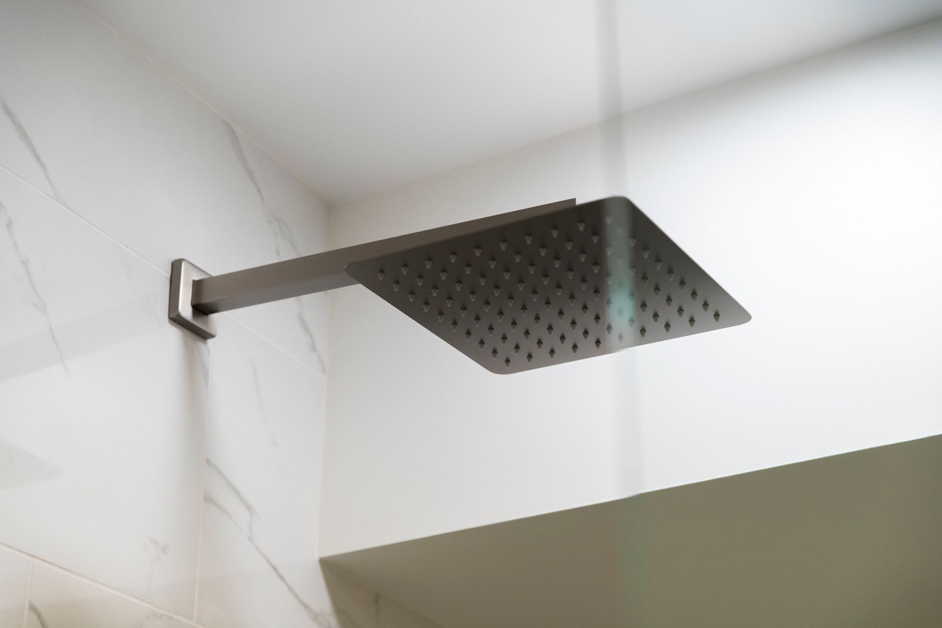 A modern square rainfall showerhead in a brushed metal finish.