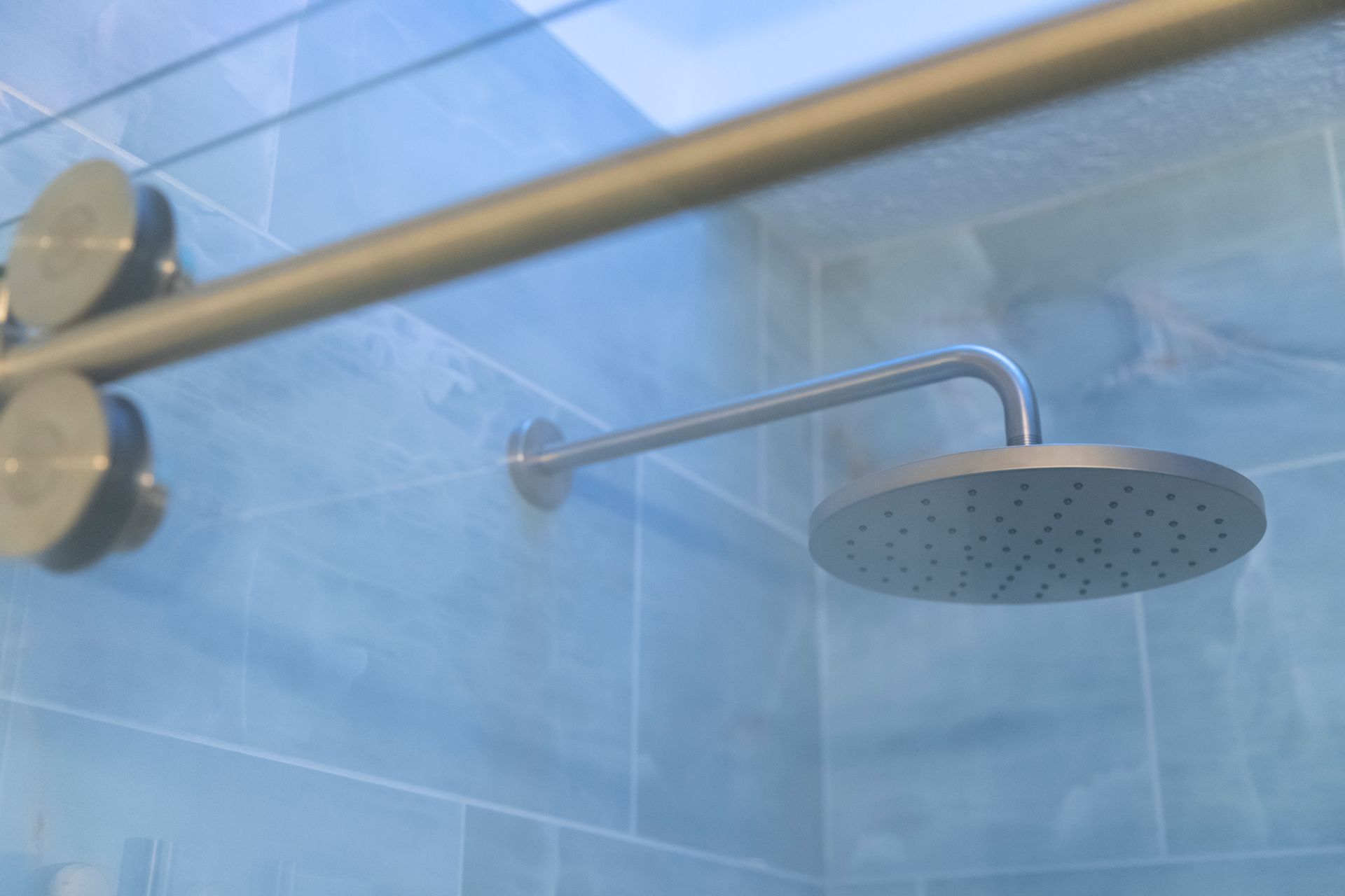 Beautifully finished custom tile shower with floor-to-ceiling tiling and a sleek, frameless sliding glass door system.