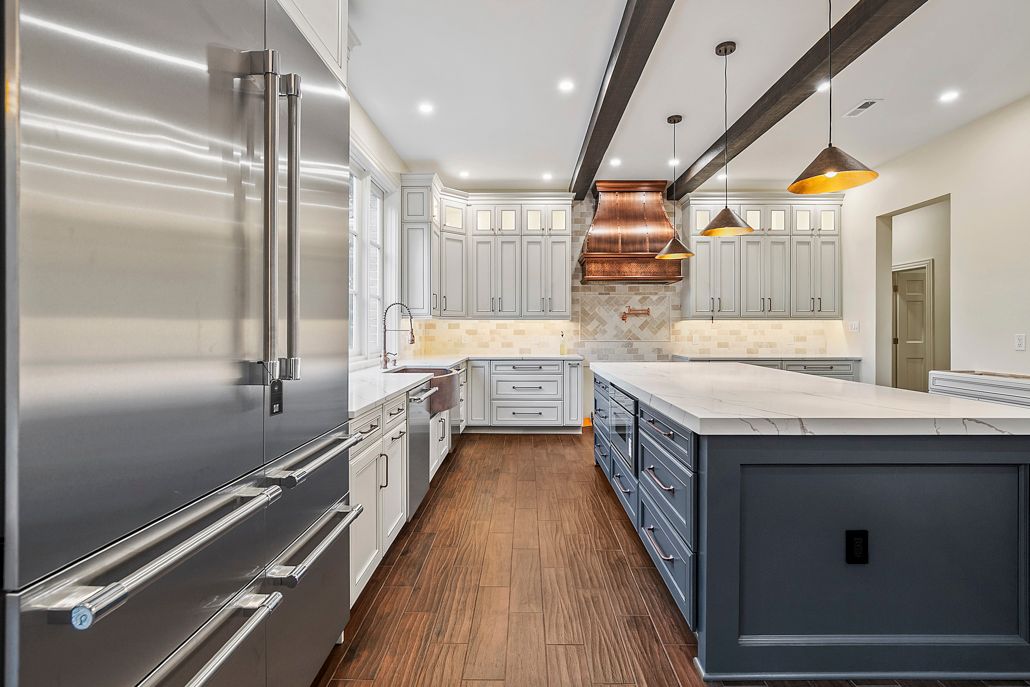 A newly renovated open-concept kitchen with a large navy blue island and a copper range hood.