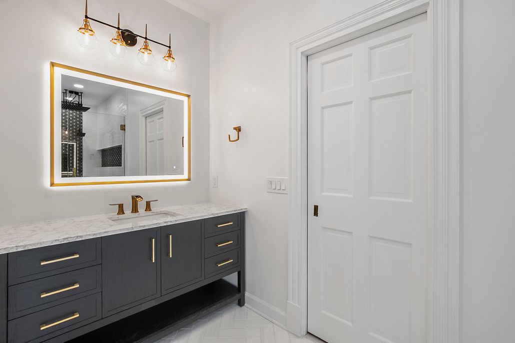 Close-up of the new black vanity with a quartz countertop, gold hardware, and a modern LED-lit mirror in Cockeysville, MD.