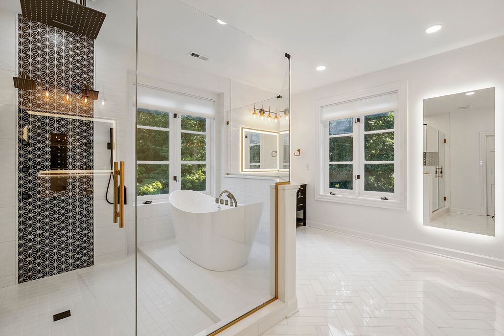 full view of the new open-concept shower area, which includes a new jacuzzi tub enclosed by glass walls on a herringbone tile floor in Cockeysville, MD.