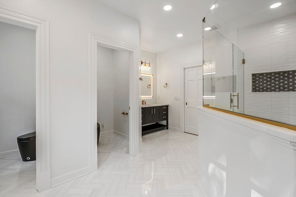 Modern bathroom with new herringbone tile and a view into one of the new, private toilet rooms in Cockeysville, MD.