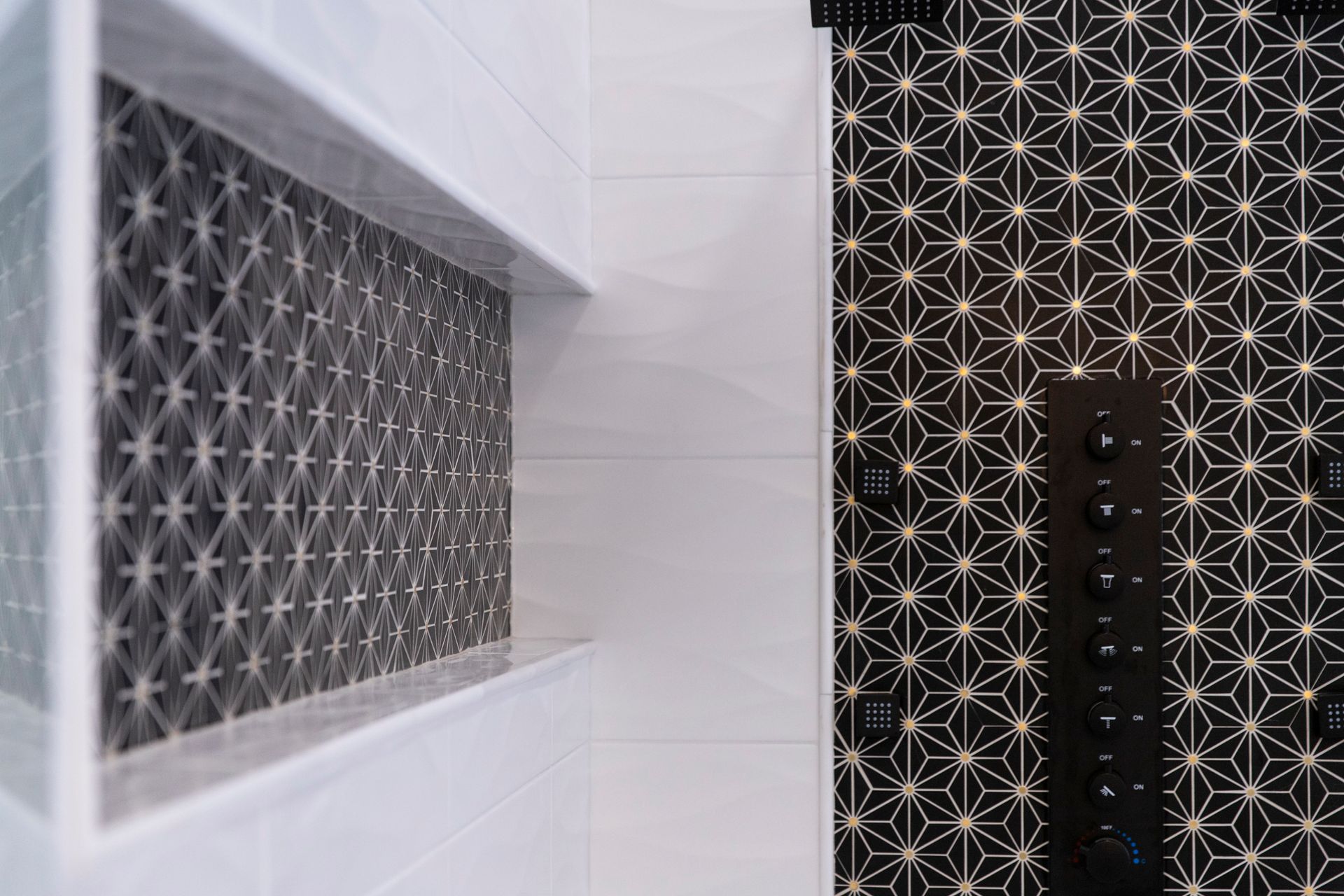 A close-up of the custom-sized shower niche with a unique black and white geometric tile, and the new black shower controls in Cockeysville, MD.