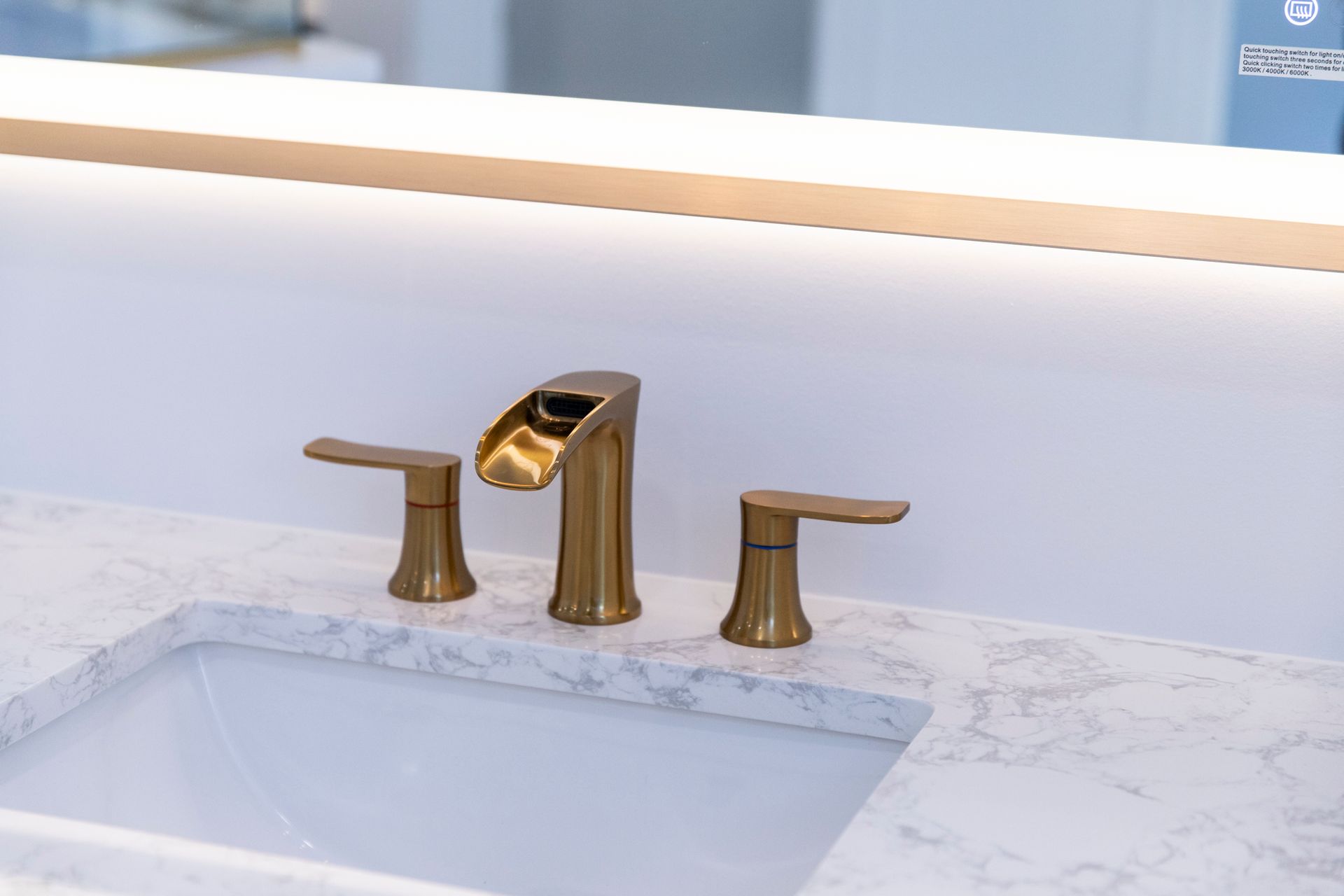 A detailed view of the new gold faucet and sink, with a focus on the modern design and illuminated mirror in Cockeysville, MD.