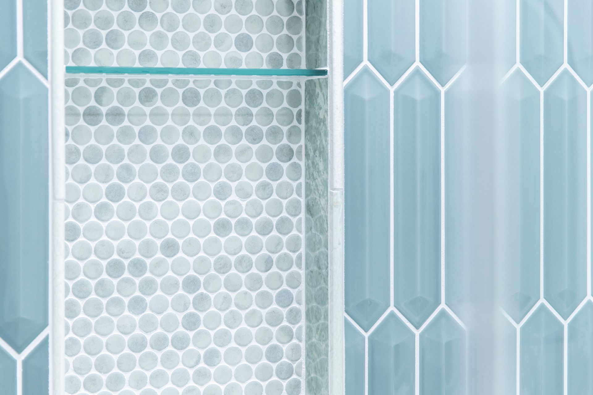 Our attention to detail: seamless recessed shower niches featuring glass shelves and penny mosaic tile for discreet, functional storage.