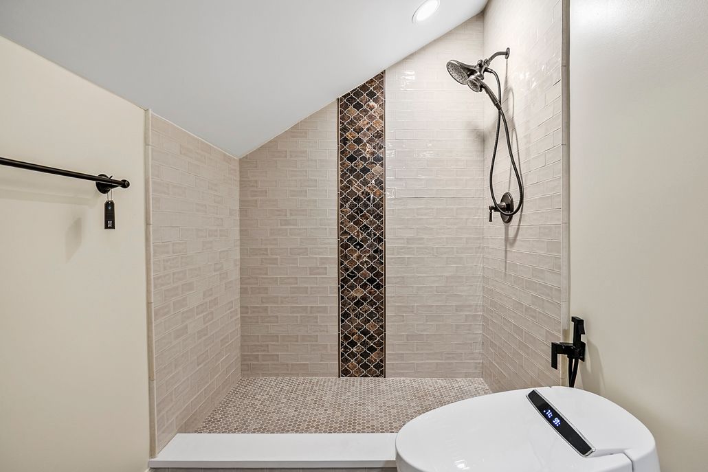 After photo of the new walk-in shower with a light subway tile and a striking vertical mosaic accent wall.