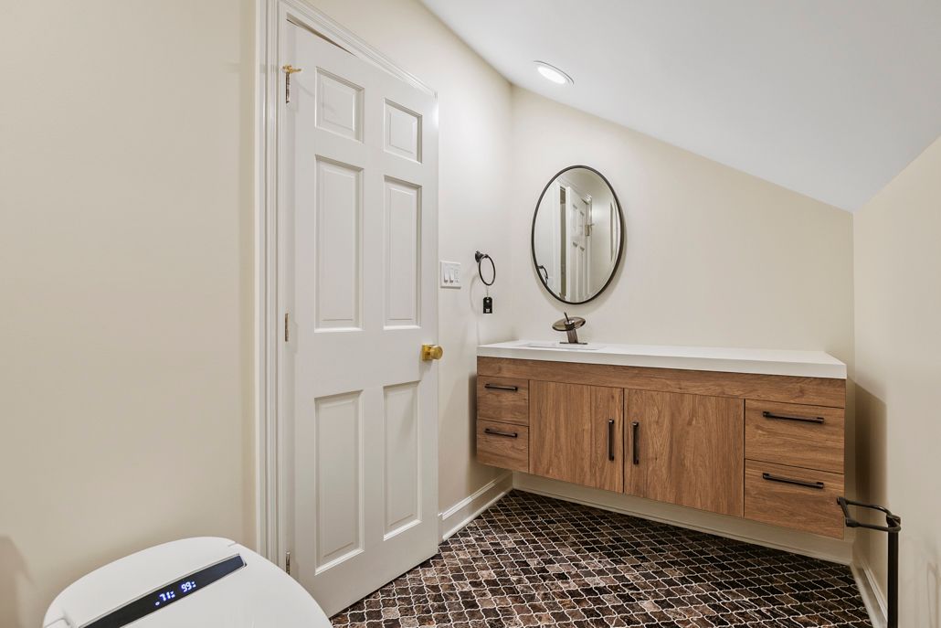 The completed bathroom remodel showing a new dark geometric floor tile, floating vanity, and a smart toilet.