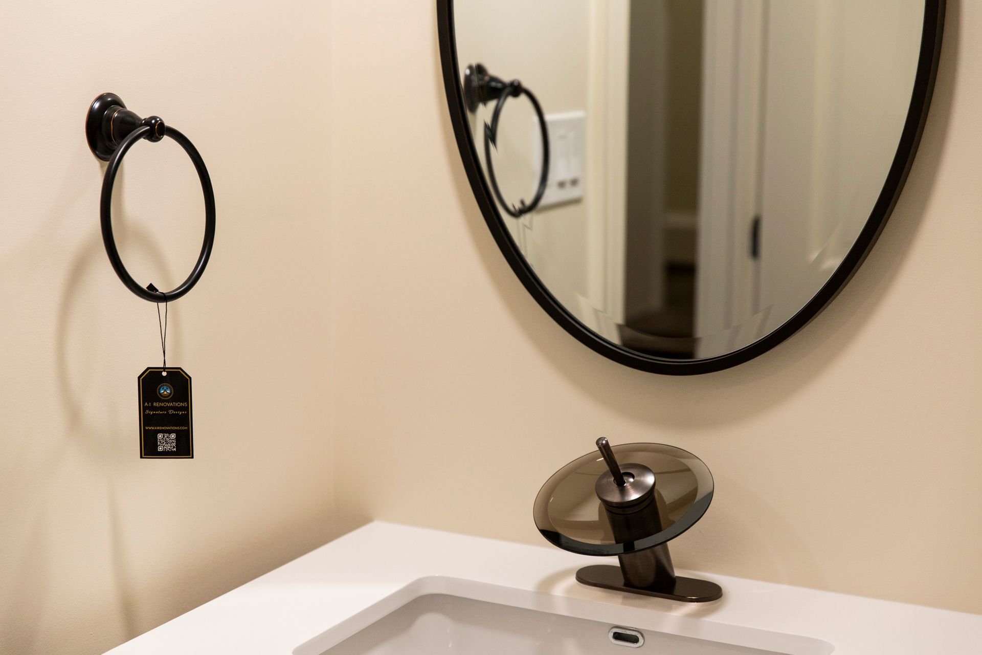 A detailed shot of the new black hardware and round mirror in the renovated Towson bathroom.