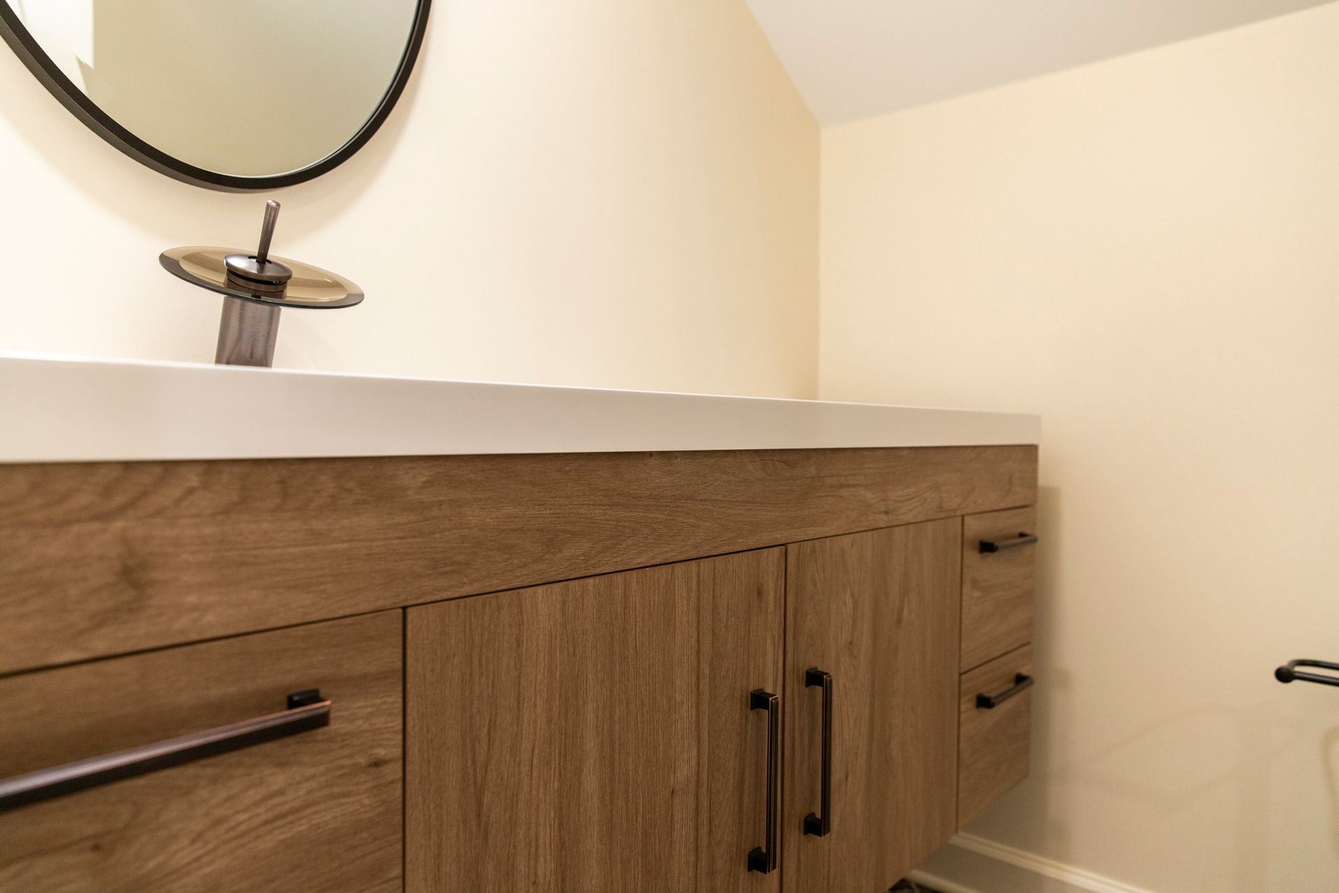 A detailed shot of the custom floating vanity's wood grain and the new black drawer pulls.