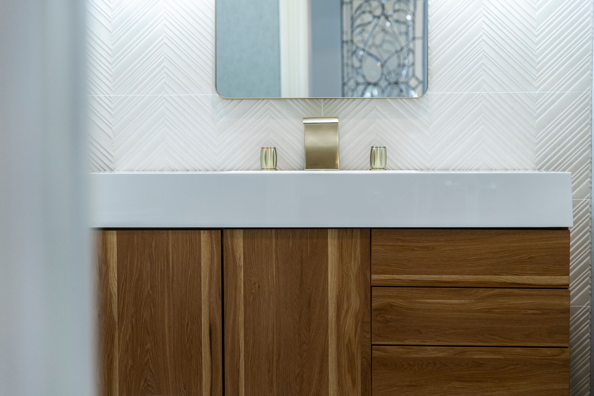 Floating wood vanity with a white sink and gold faucet.