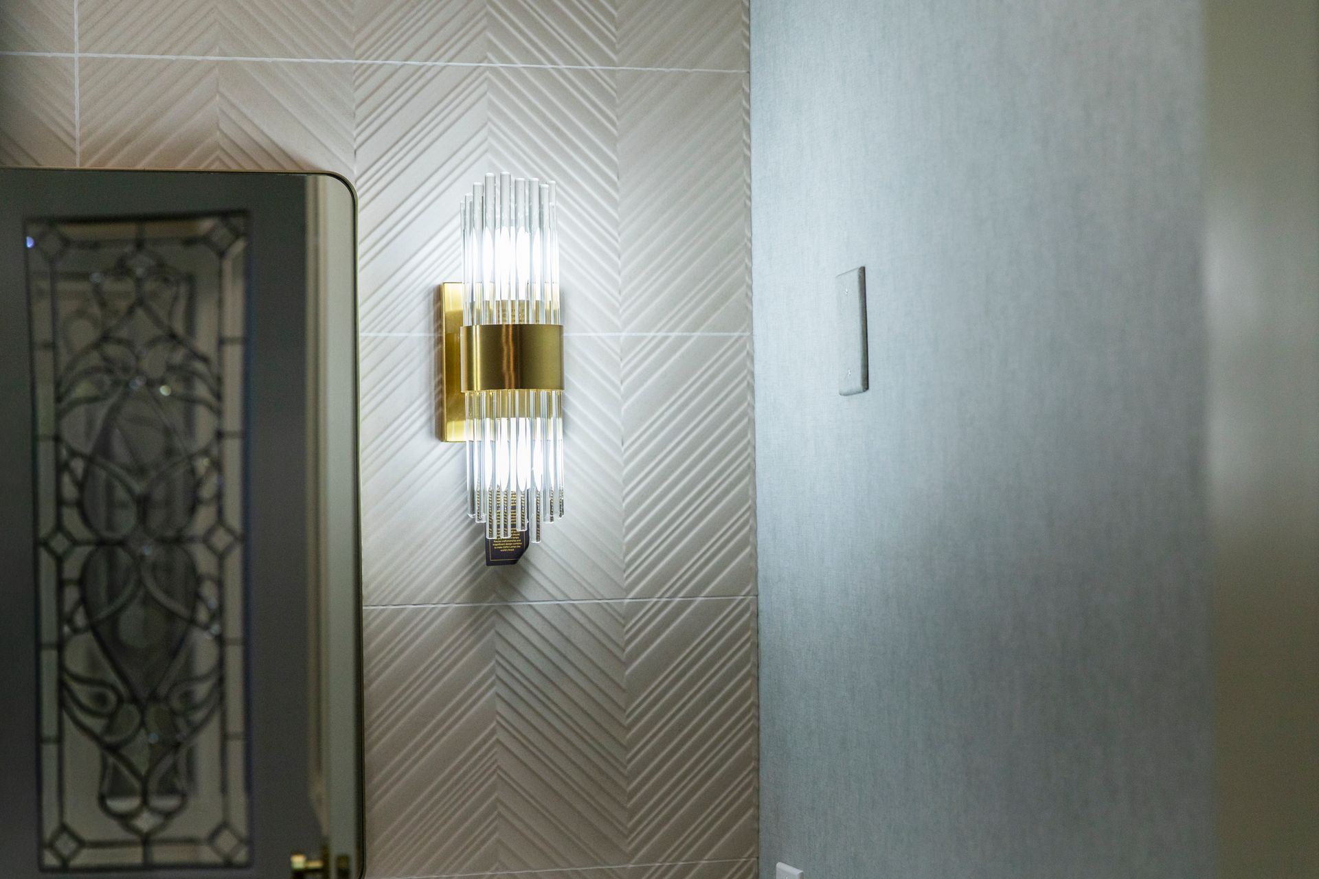 Elegant gold and glass light fixture on a textured wall.
