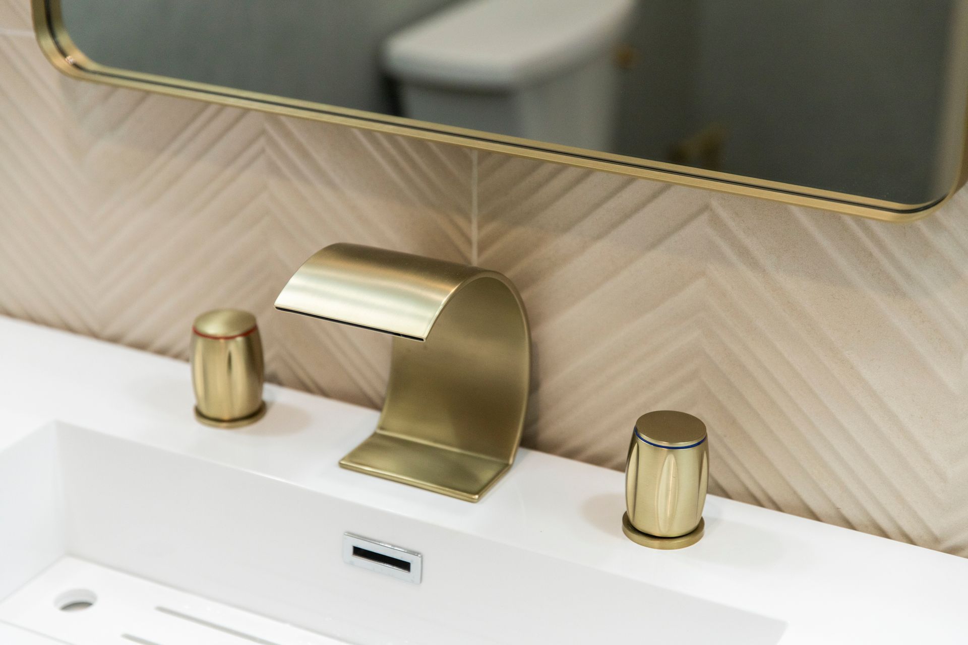 Brushed gold faucet and white sink on a modern wood vanity.