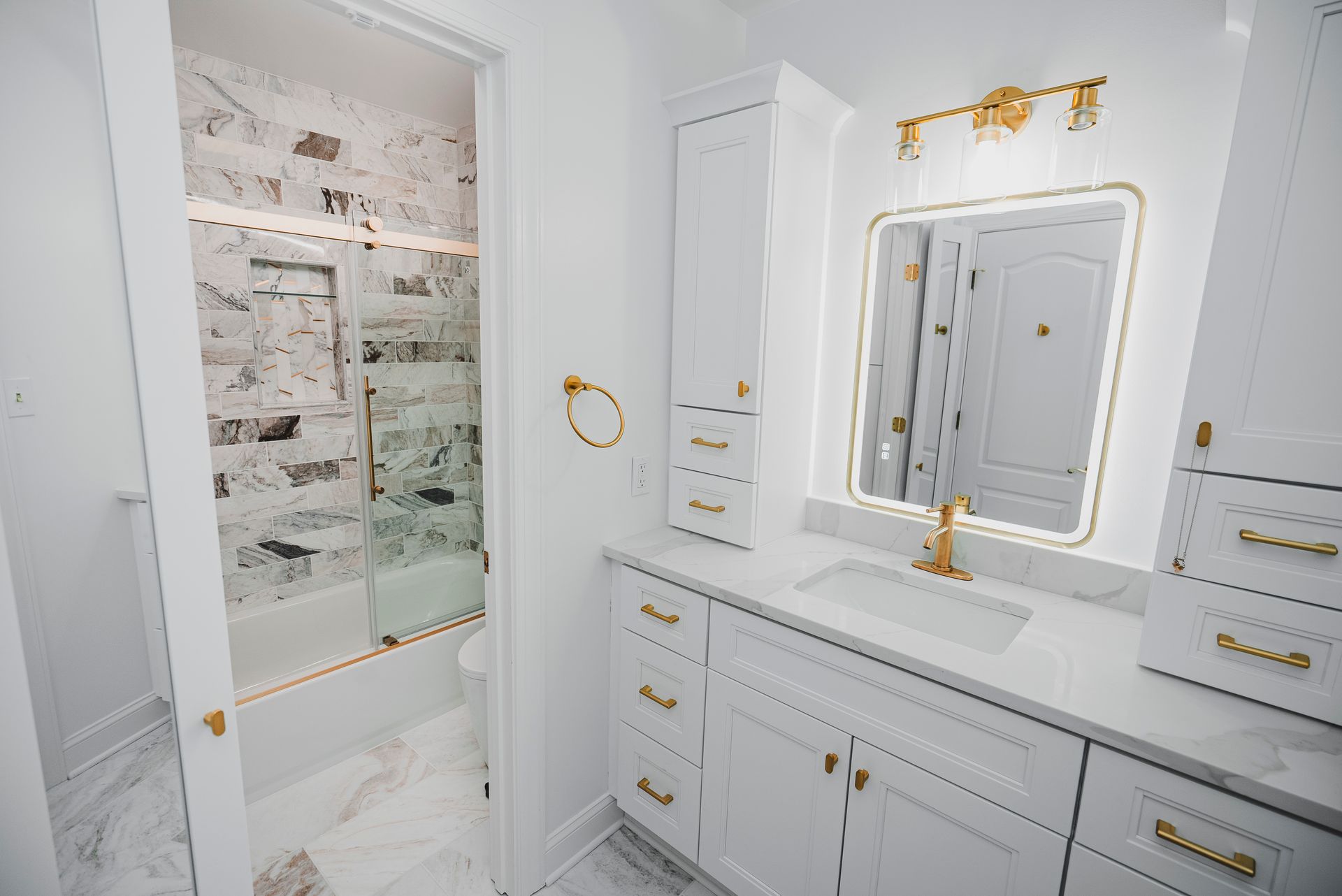 High-end bathroom remodeling project with large-format marble flooring and gold plumbing fixtures.