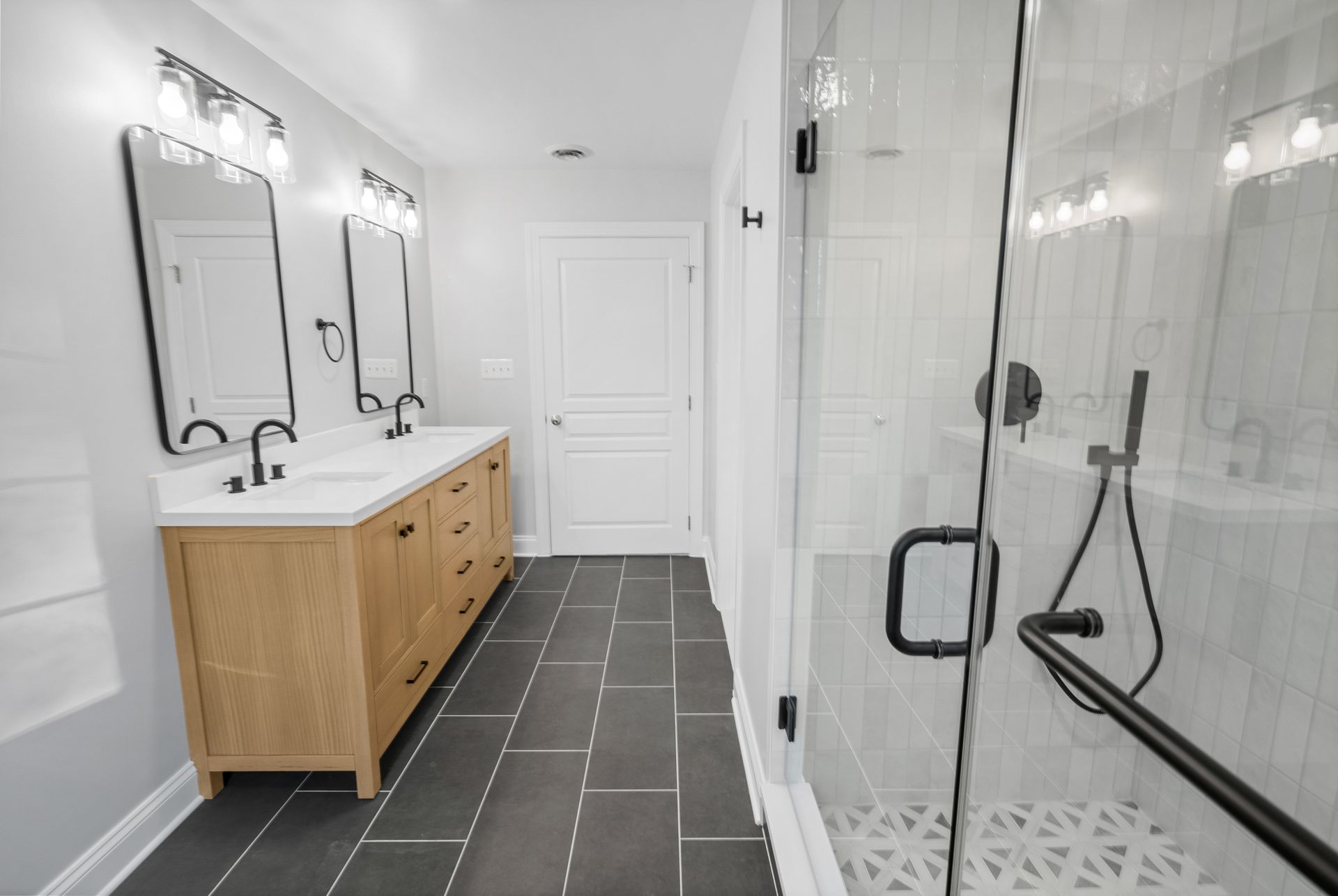 Overall view of a completed tub to walk-in shower bathroom transformation with a double vanity