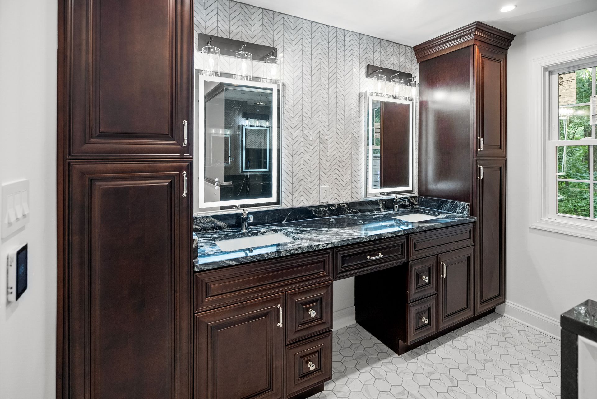 Custom rich wood double vanity with full-height storage towers and dark granite countertops
