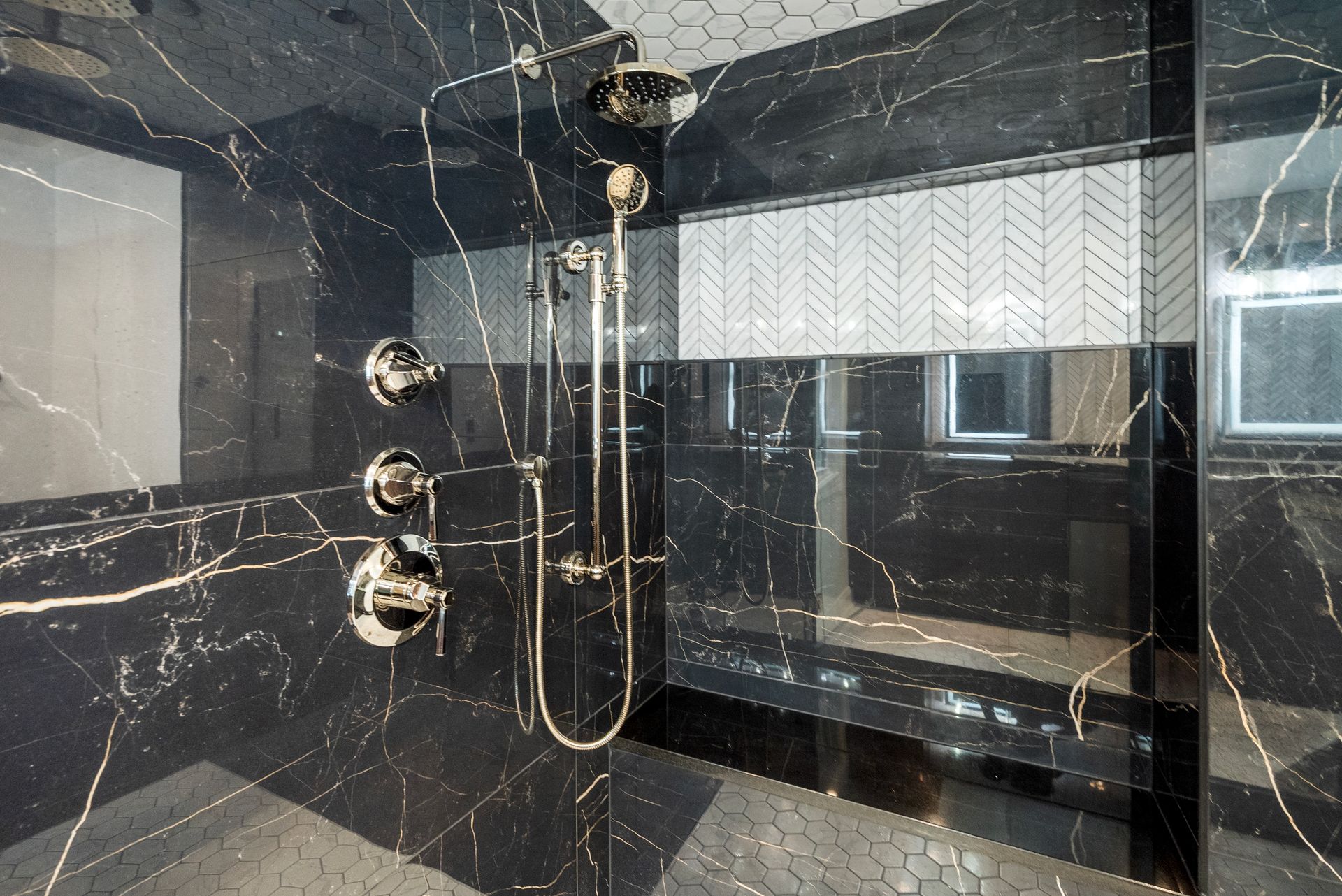 Custom white herringbone tile niche accent inside a black marble shower