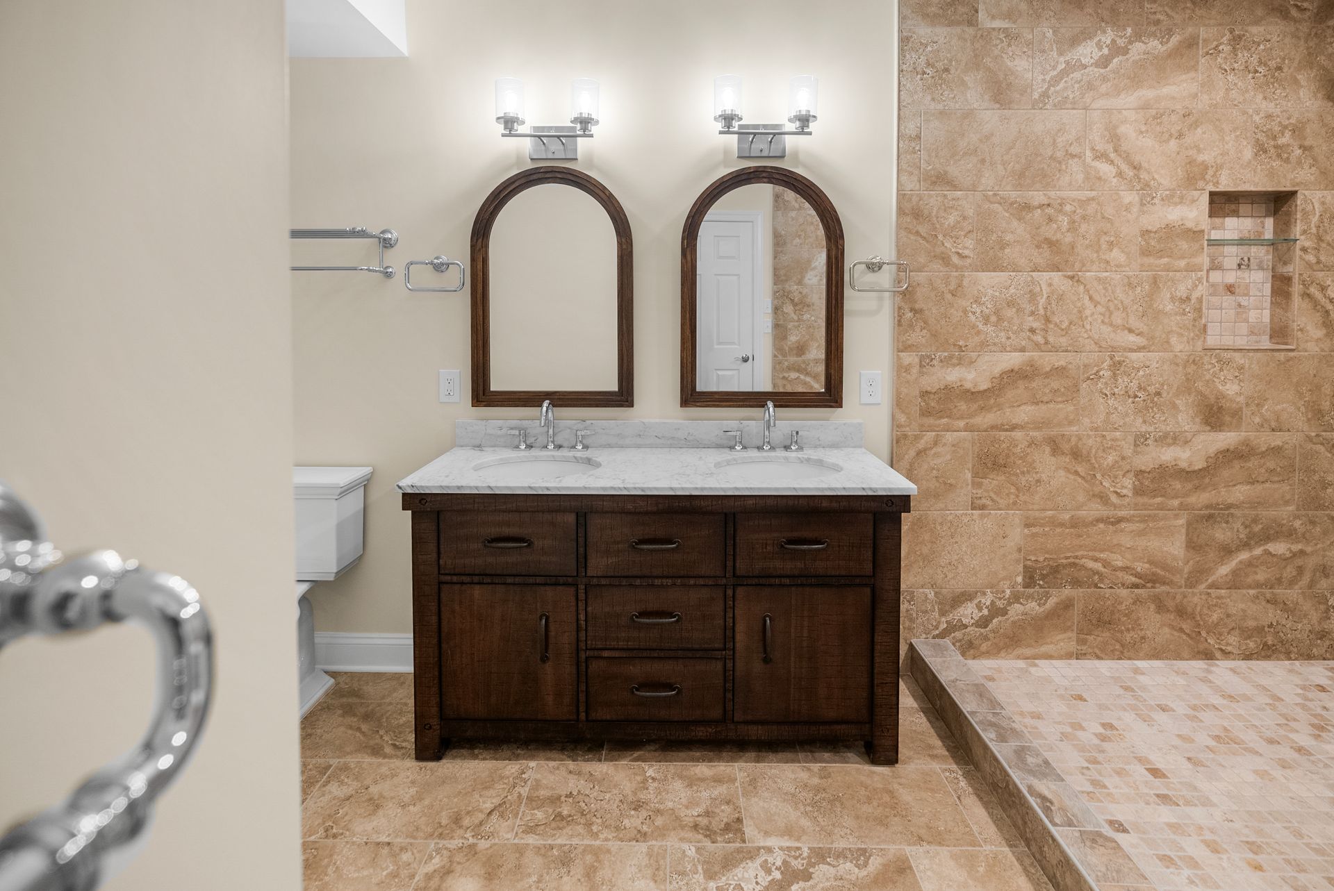 Rustic dark wood double vanity with marble countertop and twin arch-framed wood mirrors.