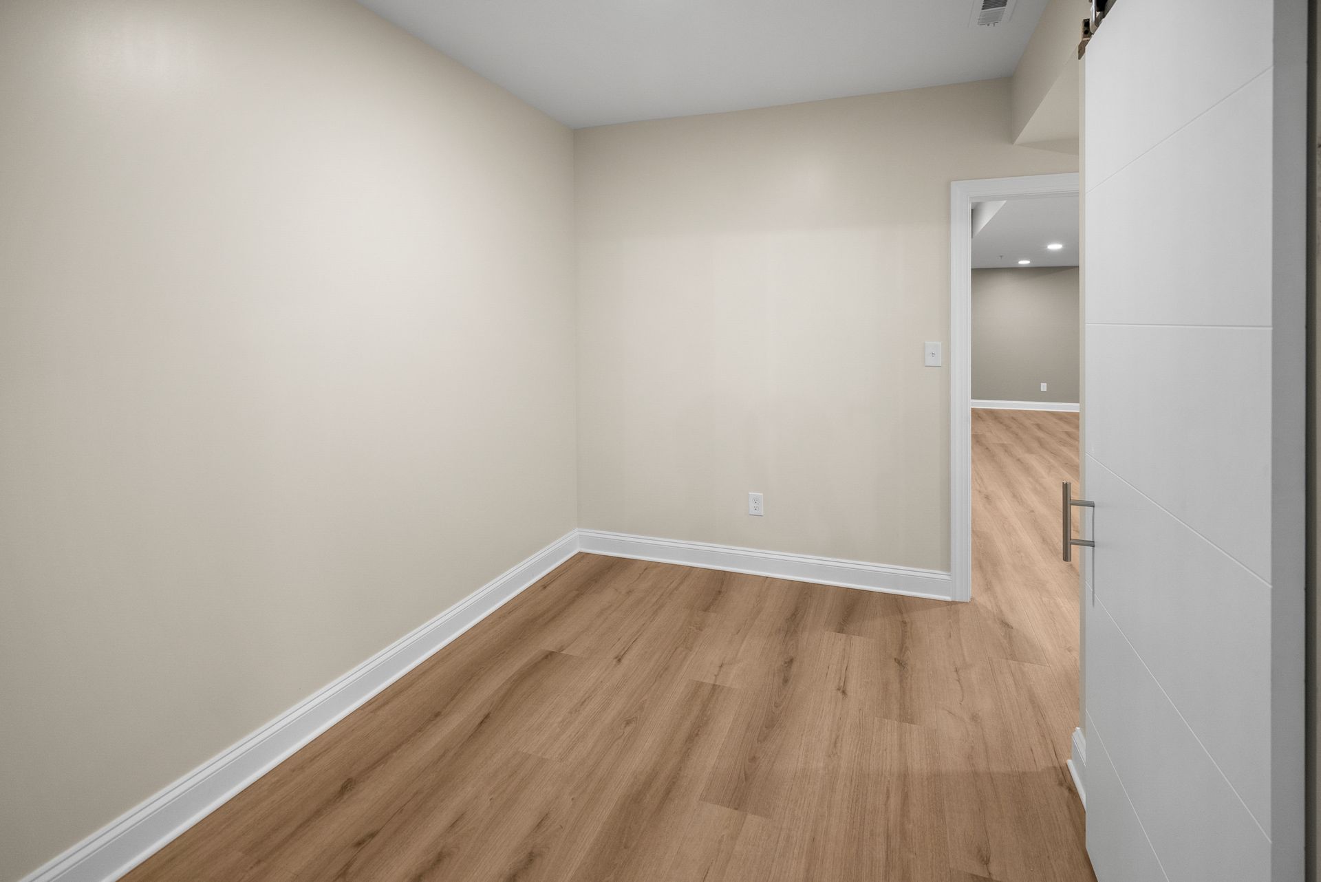 Finished basement flex room featuring neutral paint, bright lighting, and white 6-panel interior doors.